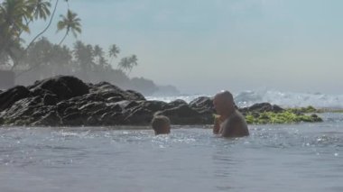 küçük çocuk kayalara okyanus suyu sıçrayan baba ile oynar