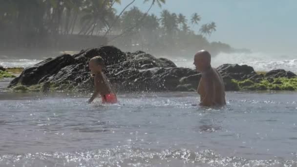 Père éclabousse l'eau sur le fils dans la mer par jour ensoleillé ralenti — Video