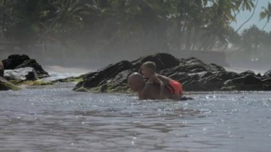baba avuç içi karşı sıcak okyanus suyunda oğlu ile at oynar
