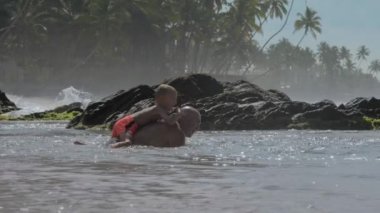 küçük çocuk masmavi okyanus suyunda geri baba üzerinde oturan dalış