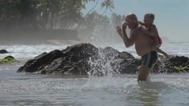 baba ve oğul palmiye ağaçlarına karşı büyük kayalar yakınında oynamak