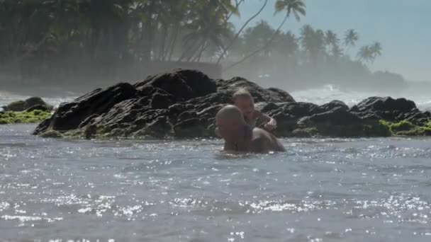 Sevimli çocuk ve baba ailesi eski kayalarda denizde oynar — Stok video