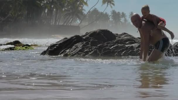 Szczęśliwy Tatuś Jumps z mały syn na tył w ocean zatoka — Wideo stockowe