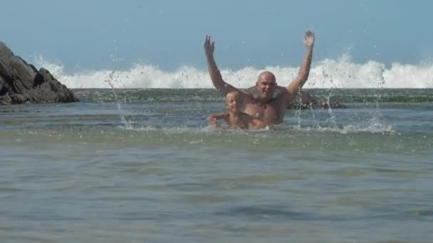 Zoon en vader splash warm zeewater in kalme ondiepe baai — Stockvideo