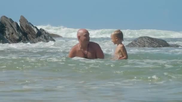Ojciec uczy małego syna do nurkowania w morzu w pobliżu starych skał — Wideo stockowe