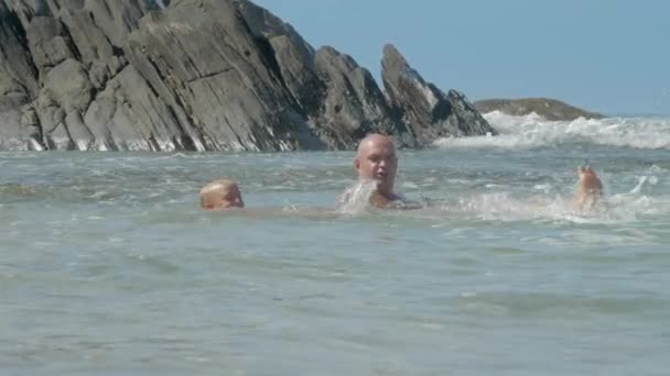 Glücklicher Papa bringt Kind an sonnigem Tag Schwimmen in der Nähe alter Klippen bei — Stockvideo