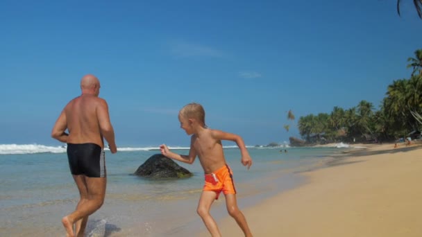 Kleiner Junge rennt um Vater herum und verbringt Zeit am Strand — Stockvideo