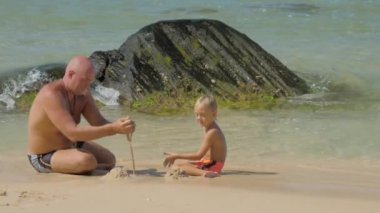 baba sahilde sevimli oğlu ile oynarken ıslak kum döker