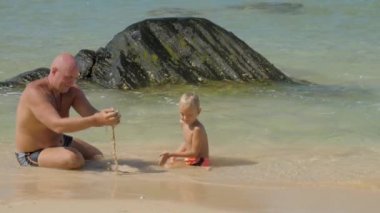 baba ile çocuk kaya da masmavi deniz suyunda oturan çalış