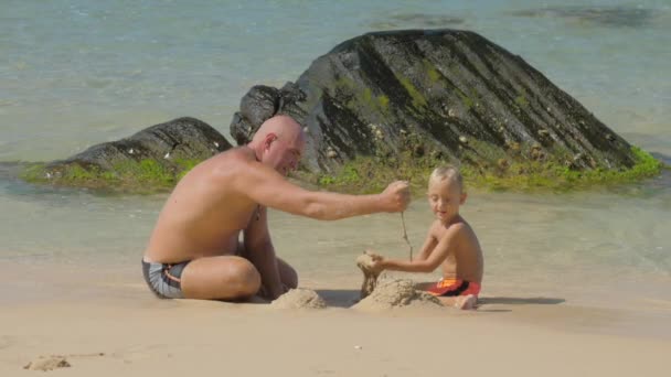 Papá y lindo chico construir con arena mojada en la playa del océano — Vídeos de Stock