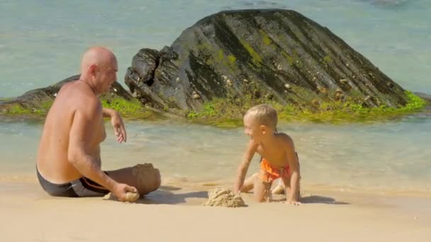 Vader gooit zand tijd doorbrengen met schattige jongen door Oceaan — Stockvideo