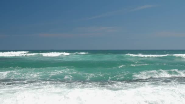Морские волны катятся по тропическому пляжу под голубым небом — стоковое видео