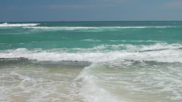青空スローモーションの下で熱帯のビーチで波が転がる — ストック動画