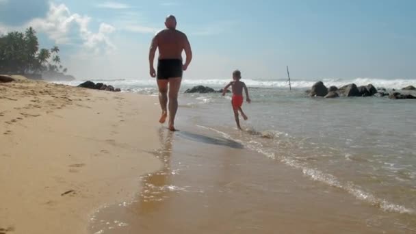 Child with daddy run in coastline against sky slow motion — Stock Video