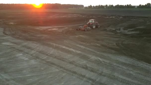 Cultivator plows field soil with harrow at sunset upper view — Stock Video