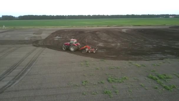 Cultivator works in field plowing fertile soil aerial view — Stock Video