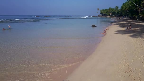 Menschen entspannen sich am Sandstrand am endlosen blauen Ozean — Stockvideo