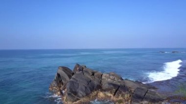 genç kadın sonsuz okyanusa karşı büyük kayalık uçurumda oturur