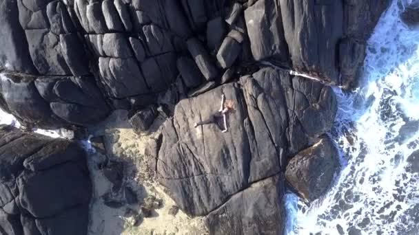 Fille en survêtement noir étire la jambe sur la falaise rocheuse grise — Video