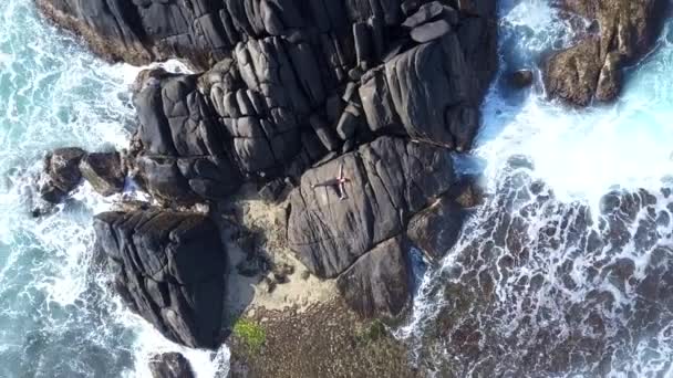 fille en survêtement étire tenant la jambe dans la main sur la roche grise 