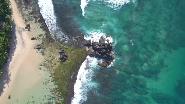 Серый скалистый скала между глубоководье океана и песчаный пляж — стоковое видео