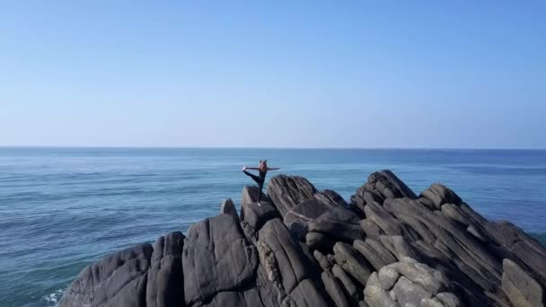 Senhora em tracksuit preto fica em ioga pose no oceano azul — Vídeo de Stock