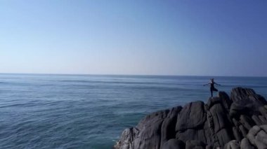 sportif kız okyanusta gri kayalık uçurumda yoga uygulamaları