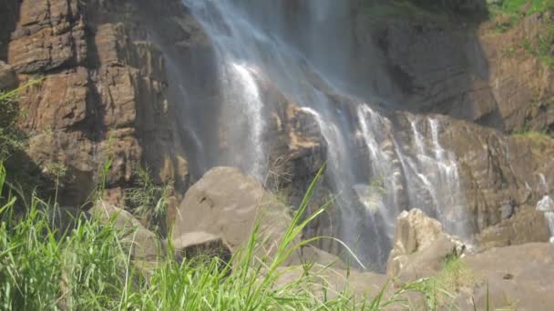 Agua dulce cae del alto acantilado rocoso marrón a la luz del sol — Vídeos de Stock