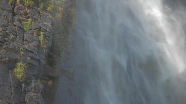 chute d'eau élevée à une falaise rocheuse brune sous un soleil éclatant 