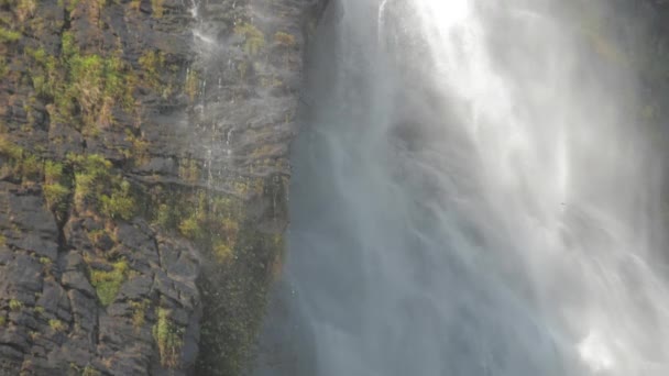 Duży wodospad otoczony klifami spada z mgłą wodną — Wideo stockowe