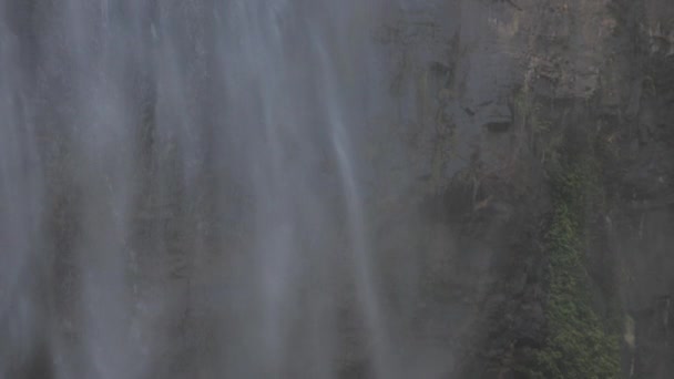 Högt vattenfall vid brunt stenigt stup under starkt solljus — Stockvideo