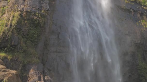 Agua cae de alto acantilado rocoso marrón con árboles verdes — Vídeos de Stock