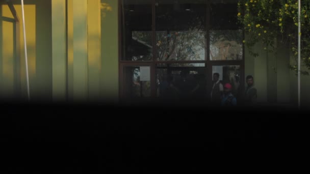 Мальчик в футболке и шортах идет к желтому входу в здание — стоковое видео