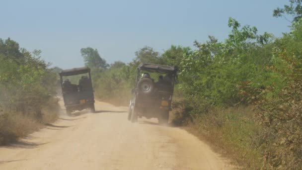 Джипы едут по коричневой грунтовой дороге оставляя облака пыли — стоковое видео