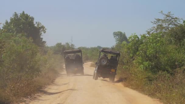 Jeeps unidad a lo largo de camino de tierra marrón dejando nubes de polvo — Vídeos de Stock