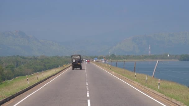 Jeep turístico conduce a lo largo de la presa asfalto carretera más allá del embalse — Vídeos de Stock