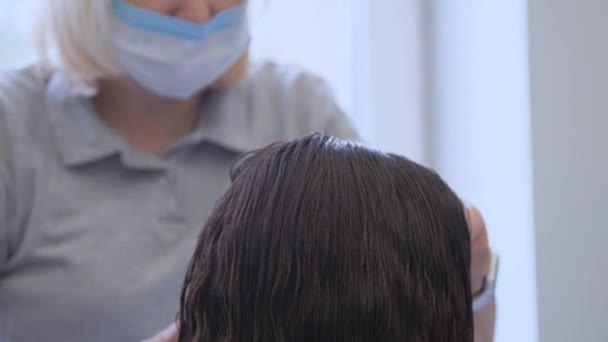 Peluquero en máscara médica disfruta de trabajar y cortar el cabello — Vídeos de Stock