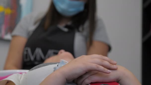 Dame ligt tegen wazig stylist in masker wassen haar — Stockvideo