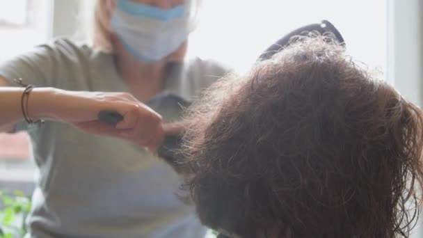 Επαγγελματίας στυλίστας ισιώνει και στεγνώνει σκούρα σγουρά μαλλιά — Αρχείο Βίντεο