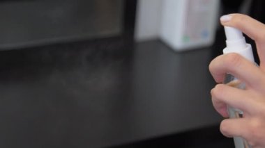 Kadın eli şeffaf bir şişe tutuyor ve dezenfektan sıkıyor.