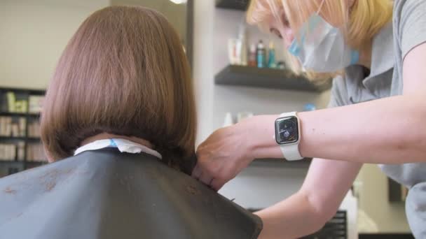 Senhora qualificada em máscara faz tiro moderno penteado escuro — Vídeo de Stock