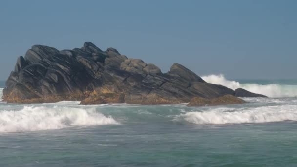 Onde oceaniche pesanti battono contro grandi pietre rocciose marrone scuro — Video Stock