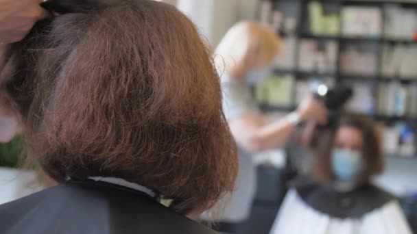 Kvinna sitter i medicinsk mask och njuter av modern frisyr — Stockvideo