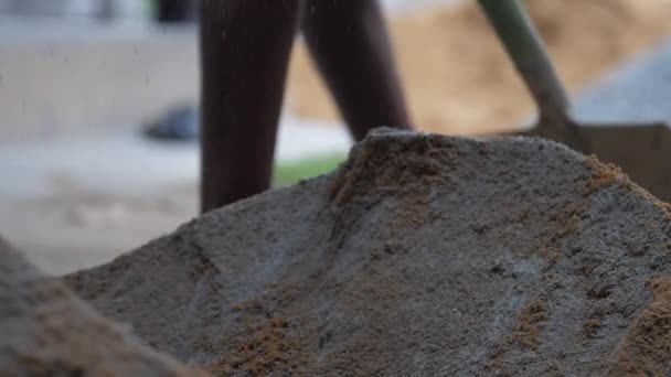Pracovník přidá písek do cementu před smícháním s kovovou lopatou — Stock video