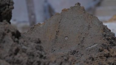 İnsan ıslak çimentoyla yerdeki metal küreği karıştırır.