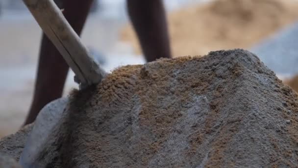 Worker adds sand to cement before mixing with metal shovel — Stock Video