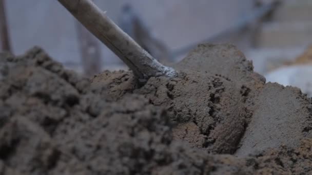 Persoon mengt natte cement met metalen schop op de grond — Stockvideo