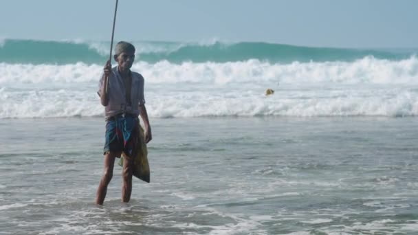 Visser houdt hengel in de hand en loopt tegen de oceaan — Stockvideo