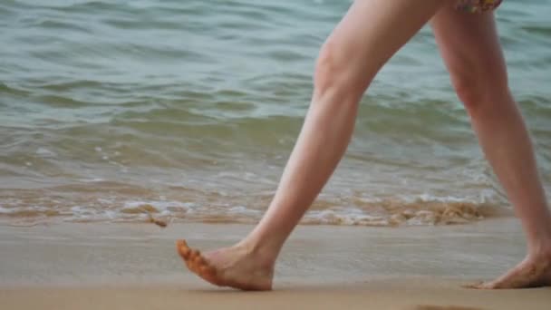 Gespierde benen lopen langs strand zand tegen golvende oceaan — Stockvideo