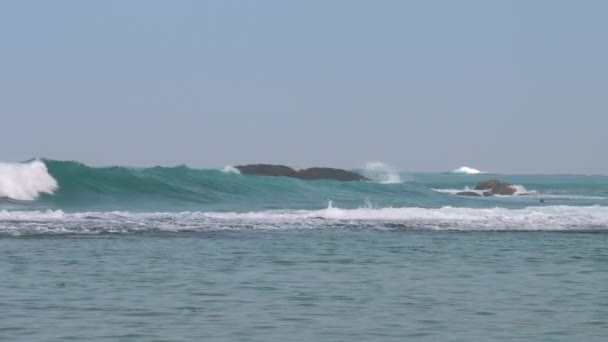 Океан с тяжелыми волнами и камнями против чистого голубого неба — стоковое видео